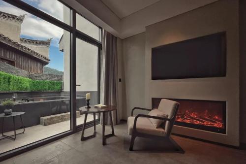 a living room with a fireplace and a chair and a table at Phoenix Hall House Hotel in Fenghuang