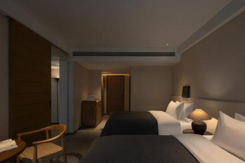 a hotel room with two beds and a table and a desk at Phoenix Hall House Hotel in Fenghuang