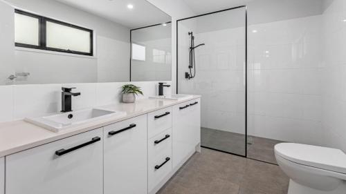 Un baño blanco con lavabo y ducha. en Sea Spray by Kingscliff Accommodation, en Kingscliff