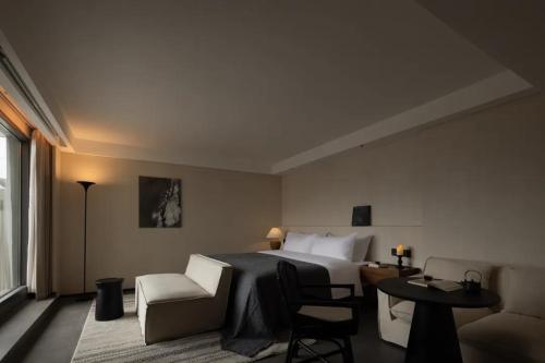 a hotel room with a bed and a table and chairs at Phoenix Hall House Hotel in Fenghuang