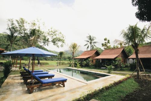 a pool with two lounge chairs and an umbrella at Bhalance Retreat in Padangbai