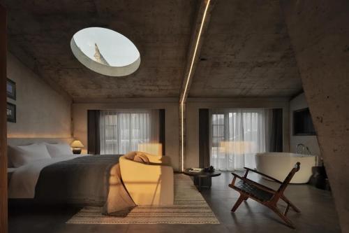 a bedroom with a bed and a chair and a mirror at Phoenix Hall House Hotel in Fenghuang