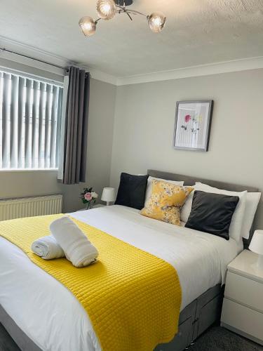 a bedroom with a large bed with a yellow blanket at Peaceful 3 Bed Home in Basildon