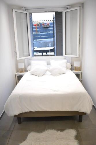 une chambre avec un grand lit blanc avec une fenêtre dans l'établissement Appartement Marseille, à Marseille