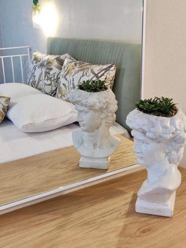 two white statues sitting on a floor in front of a mirror at Theros Summer Suite 1 in Nikiti