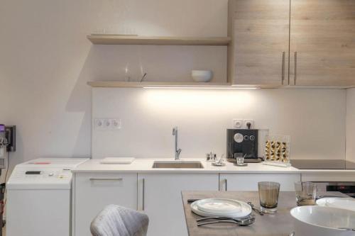 une cuisine blanche avec un évier et un comptoir dans l'établissement Superbe studio, Tête d'or, Lyon, à Lyon