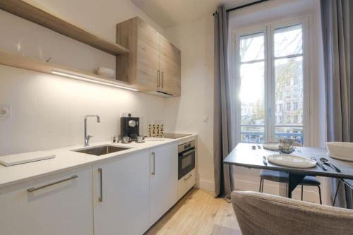 - une cuisine avec des placards blancs, un évier et une table dans l'établissement Superbe studio, Tête d'or, Lyon, à Lyon