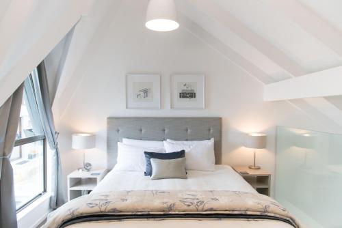 a bedroom with a large white bed with two lamps at Aria on Bank in Dunedin