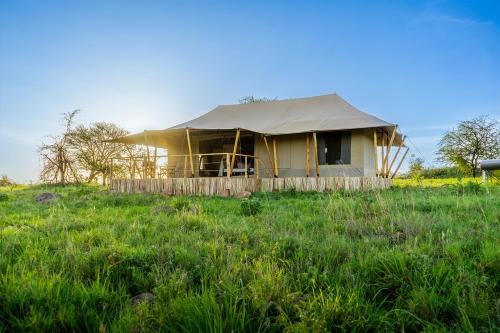 a yellow house with a tarp on top of a field at Serengeti Malaika Luxury Camp in Serengeti National Park