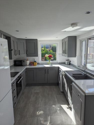 a large kitchen with gray cabinets and a window at Prospect House - Elegant 4-Bed Family Escape Near Ward Park & Marina in Bangor