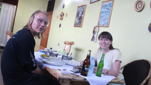 a man and a woman sitting at a table with beer bottles at Kibale Eco-Home in Bigodi