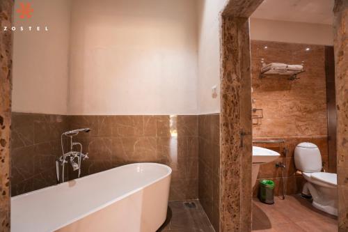 a bathroom with a tub and a toilet at Zostel Plus Lonavala in Lonavala