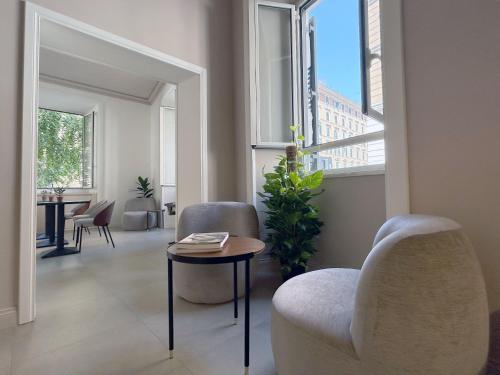 sala de estar con 2 sillas, mesa y ventanas en Astom Suites, en Roma