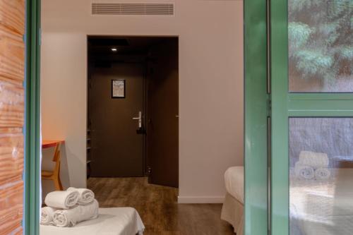 a room with a door and a bed and towels at Logis Hôtel Domaine du Moulin Cavier - Restaurants & Spa in Avrillé