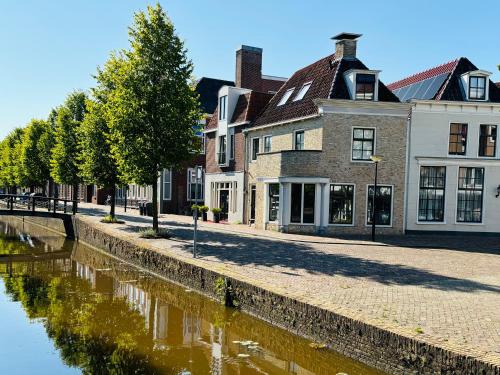 a street next to a river with buildings at Stadshotel DE ACADEMIE in Franeker