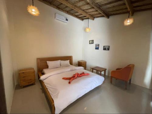 a bedroom with a bed with a red robe on it at La Boheme Mini in Gili Trawangan