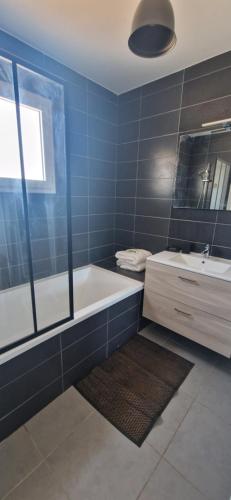 La salle de bains est pourvue de carrelage bleu, d'une baignoire et d'un lavabo. dans l'établissement Maison Pierres de Provence, à Saint-Cannat