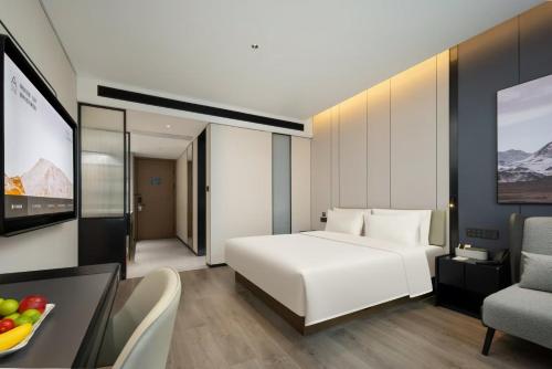 a hotel room with a white bed and a television at Atour Hotel Dongguan Huangjiang Xingguang Road in Dongguan