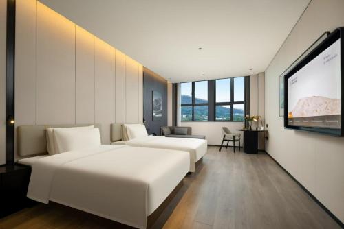 a hotel room with two beds and a flat screen tv at Atour Hotel Dongguan Huangjiang Xingguang Road in Dongguan