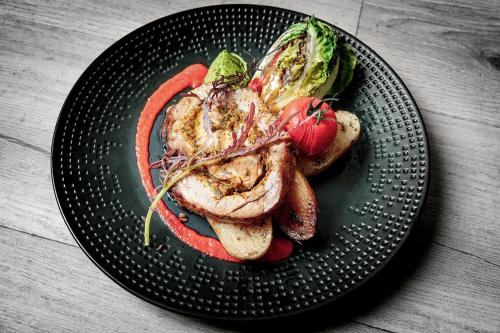 a black plate with meat and vegetables on a table at Hôtel L'Escale Marine Valdys Resort & SPA in Douarnenez