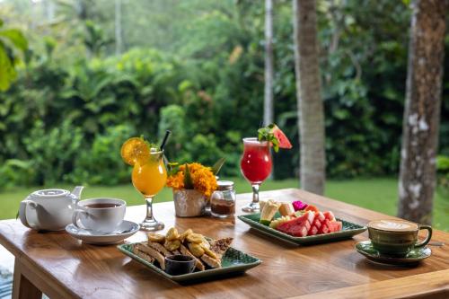 una mesa de madera con dos platos de comida y bebida en The Mesare Eco Resort, en Nusa Penida