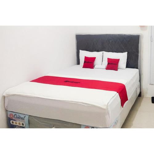 a bed with two red pillows on top of it at RedDoorz near Grand Tarakan Mall in Klapa