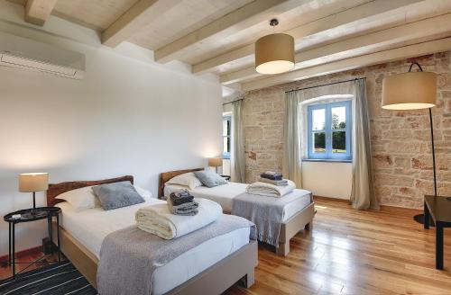 a bedroom with two beds and a brick wall at Villa PI for 8 people in Central Istria with heated pool & large garden in Tinjan