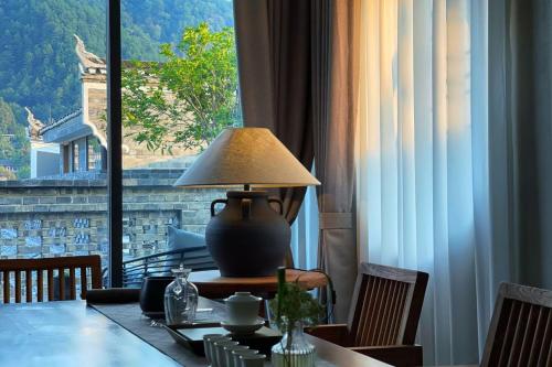 a table with a lamp on a table with a window at Phoenix Hall House Hotel in Fenghuang