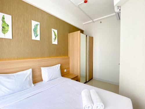 a bedroom with a bed with two towels on it at Best Homey 1BR at 25th Floor Vasanta Innopark Apartment By Travelio in Cikarang