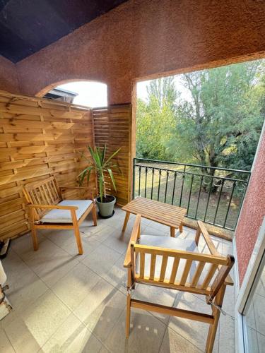 un patio avec deux chaises et une table sur un balcon dans l'établissement Studios aux hameaux de Camargue, à Arles