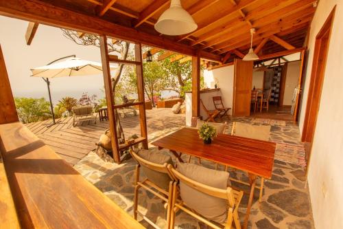 a patio with a wooden table and chairs and an umbrella at Casa la Roseta in Alajeró