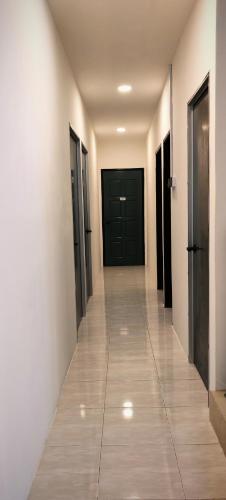 a hallway with black doors and a tile floor at 23 Inn Singlebed Share Bathroom No Window in Bukit Mertajam
