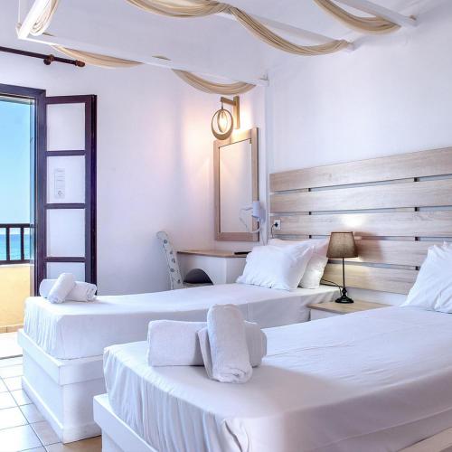 two beds in a room with white walls at Elmi Beach Hotel & Suites in Hersonissos