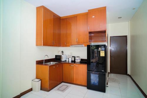 a kitchen with wooden cabinets and a black refrigerator at Le Ans Haven fully-furnished homestay in Puerto Princesa City