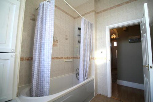 a bathroom with a tub and a shower with a shower curtain at Birmingham - Bungalow - Sleeps6 - Garden - Parking in Birmingham