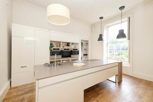 a kitchen with white cabinets and a large island at JOIVY Exclusive house with free parking in Edinburgh