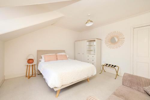 a white bedroom with a bed and a chair at JOIVY Exclusive house with free parking in Edinburgh