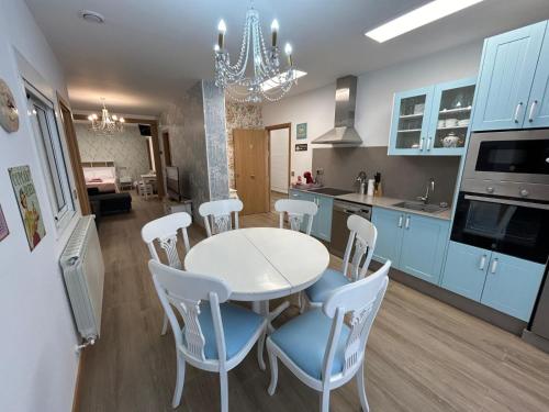 een keuken met blauwe kasten en een witte tafel en stoelen bij Apartamentos Torres del Milladoiro in Amés