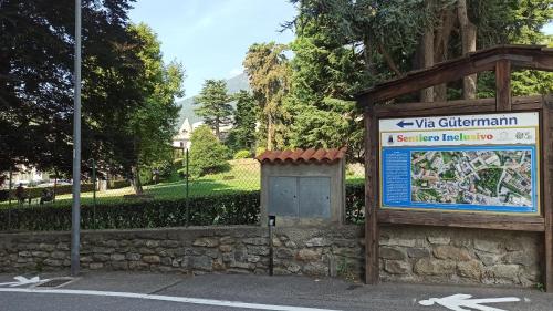 a sign in a park next to a stone wall at Casa Stella Terminal in Perosa Argentina