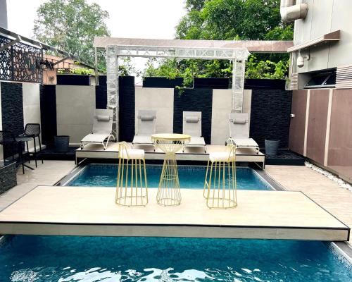 a swimming pool with two chairs and a table and a table and a table at Hotel La Falaise Bonapriso in Douala