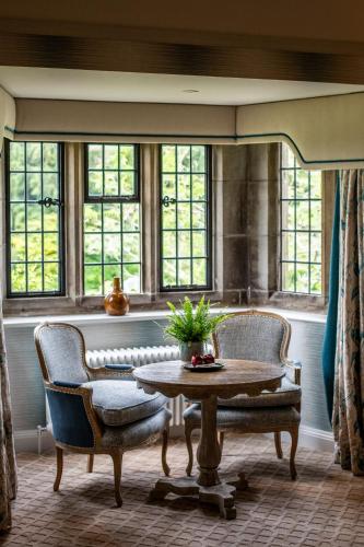 a room with two chairs and a table and windows at Mallory Court Country House Hotel & Spa in Leamington Spa