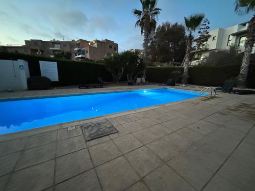 a blue swimming pool in a yard with palm trees at Seaview apartment with garden & pool in Paphos City