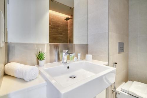 a white bathroom with a sink and a mirror at Lagom Vacation Home 2 Bedroom Apartment Blue Waters in Dubai