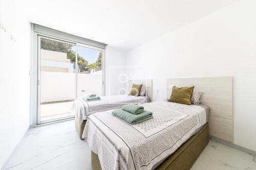 two beds in a white room with a window at Villa Coral deluxe oasis by OYOOSTAYS in Torrevieja