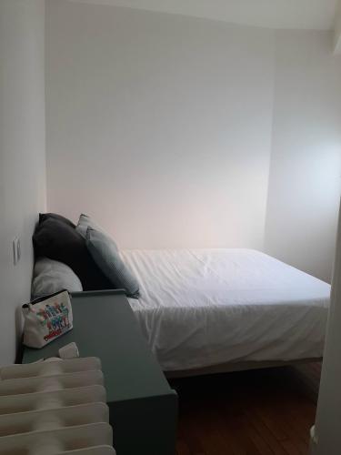 - une chambre avec un lit doté de draps blancs et d'une table dans l'établissement Très beau studio Paris 15, proche des commerces et de la tour Eiffel, à Paris