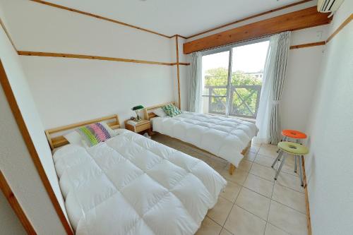 1 Schlafzimmer mit 2 Betten und einem großen Fenster in der Unterkunft Lulaliya in Ishigaki-jima