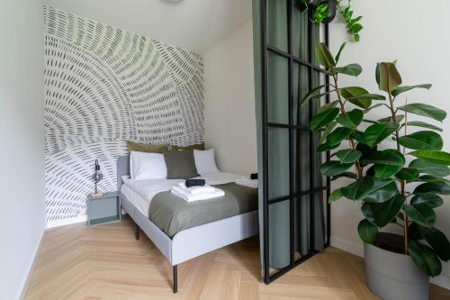 a bedroom with a bed and a large plant at Verde Kato Apartment Francuska - FREE PARKING - Self check-in in Katowice