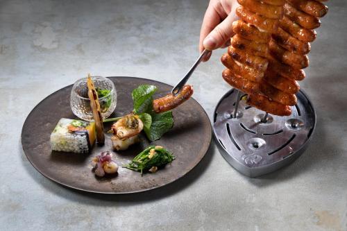 a person is eating food on a plate with tentacles at Ichiraku tendo spa & brewery in Tendo