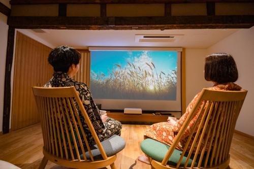 two women sitting in chairs watching a presentation on a screen at Ichiraku tendo spa & brewery in Tendo