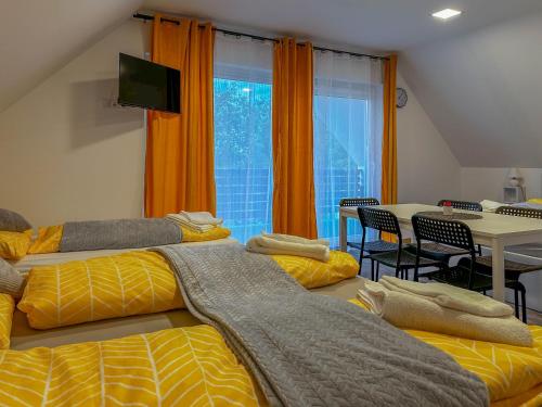 a room with two beds and a dining room with a table at See Panzió in Fertőrákos
